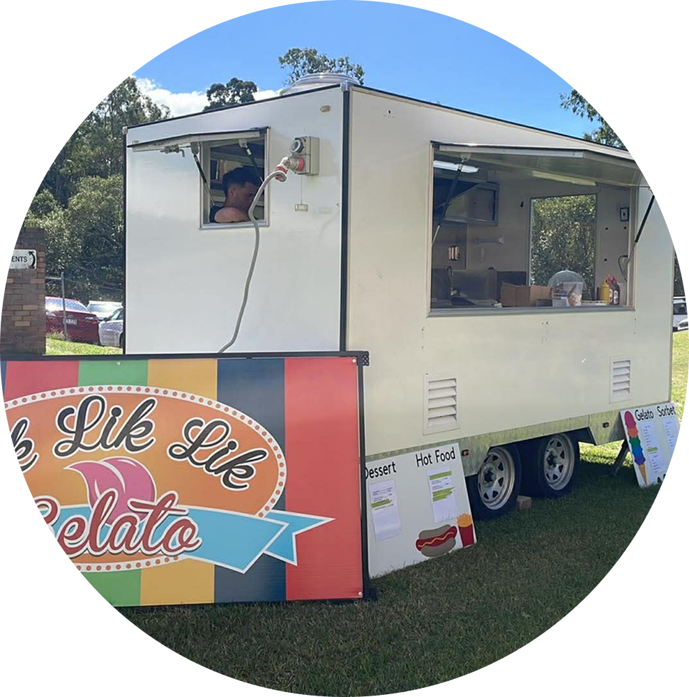 Lik Lik Lik Gelato trailer set up on the grass with the branded signboard out front